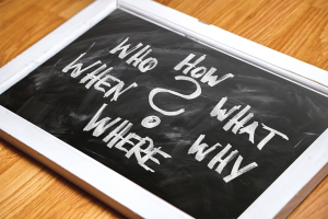 Blackboard with the words "How, What, Why, Where, When Who" written on it.